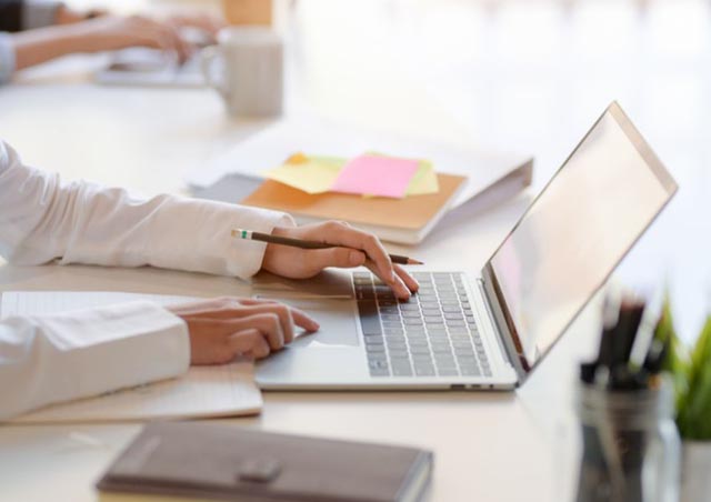 person-writing-notes-and-researching-on-a-laptop person-writing-notes-and-researching-on-a-laptop